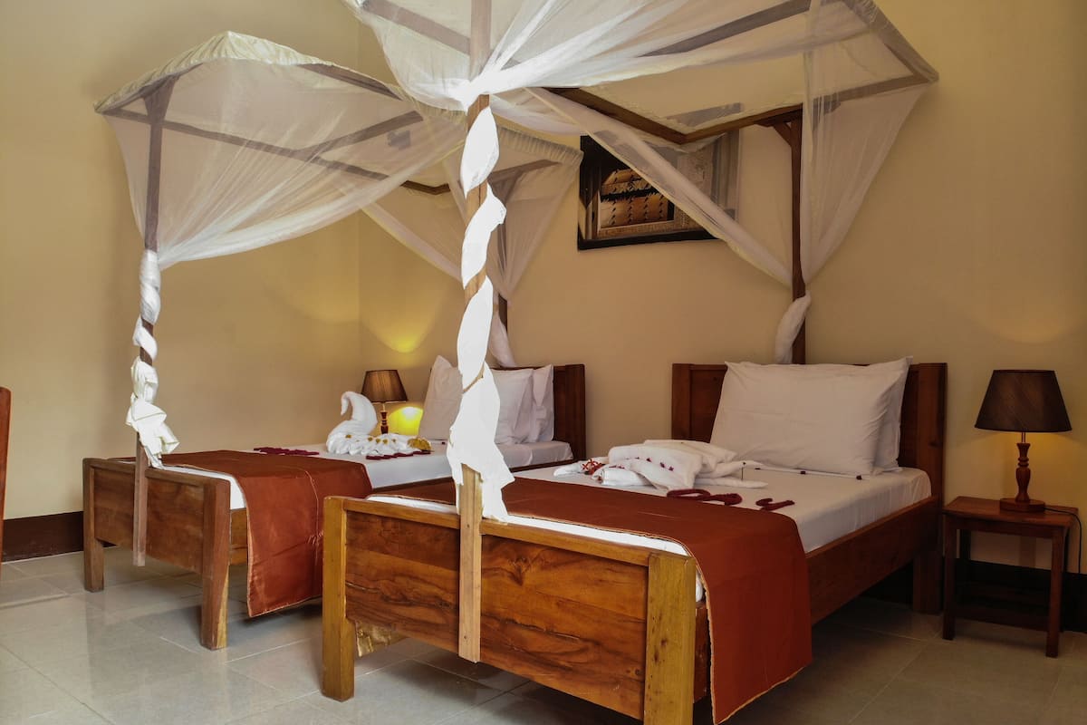 Ein Schlafzimmer mit einem hölzernen Bett, einem Nachttisch, einem Beistelltisch und einem Himmelbett mit weißem Baldachin.