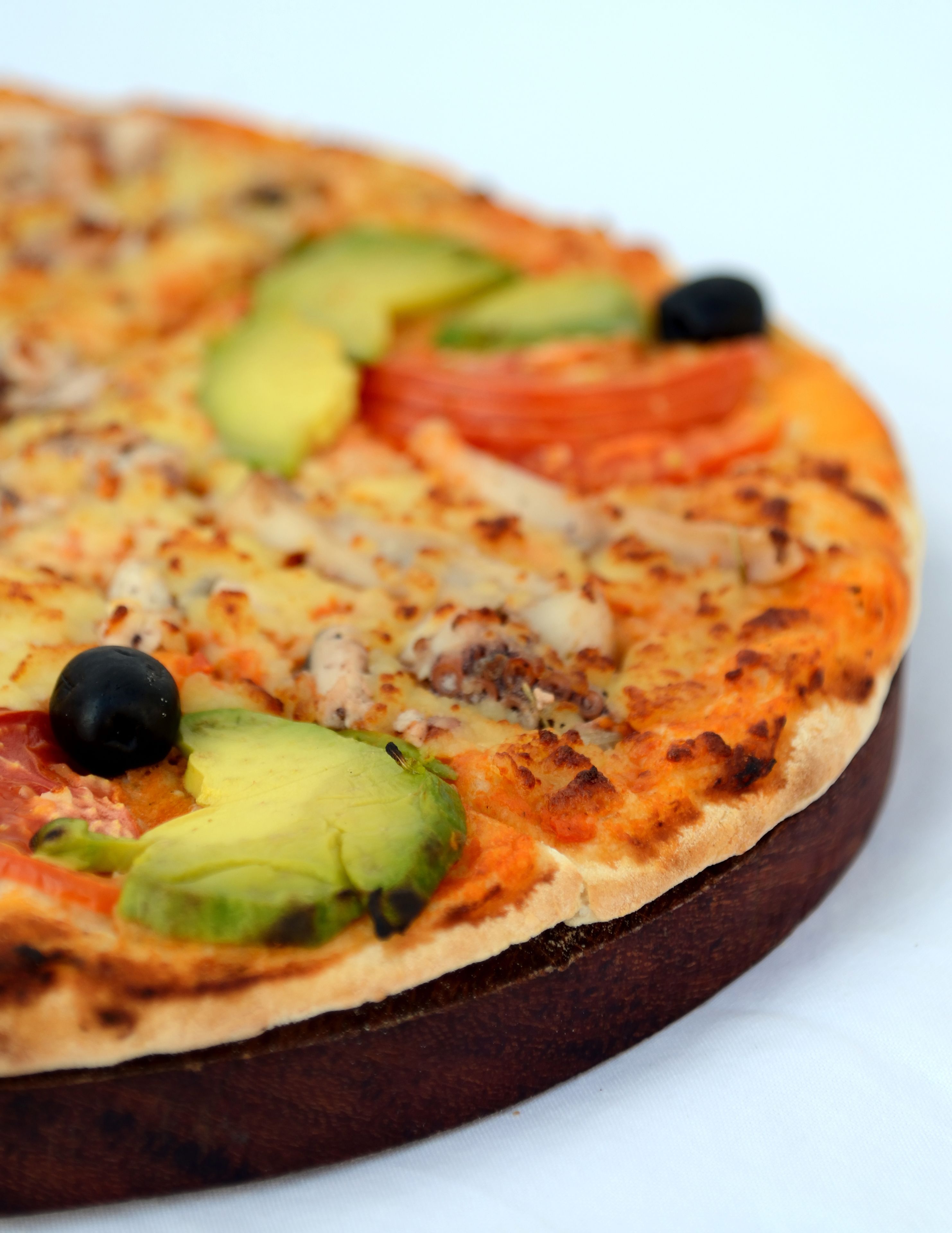 A pizza with toppings on a wooden board.