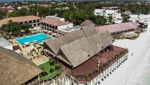 A resort with a swimming pool, outdoor seating, and a beach area.