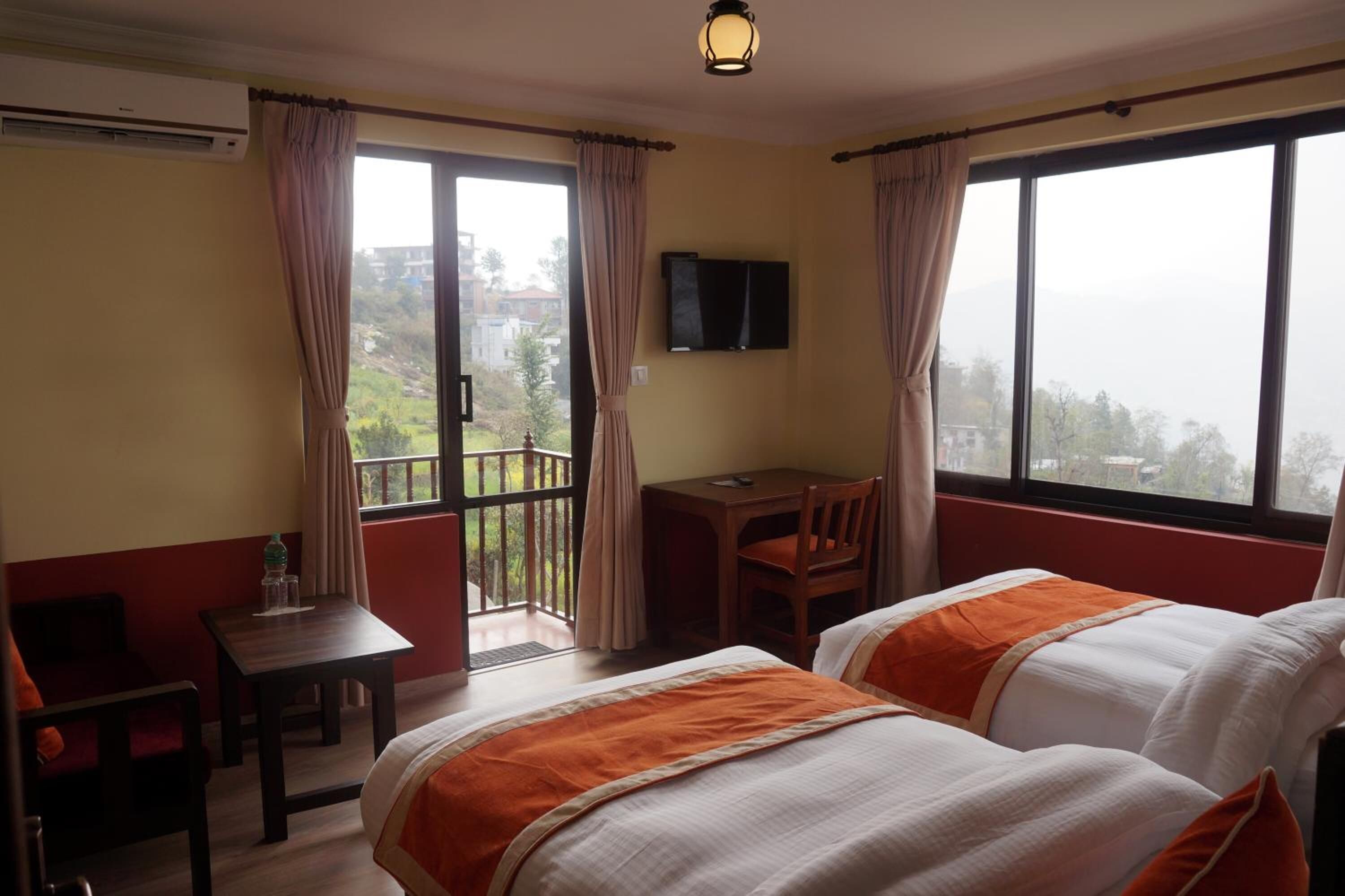 A hotel room with two beds, a desk, a chair, and a TV.