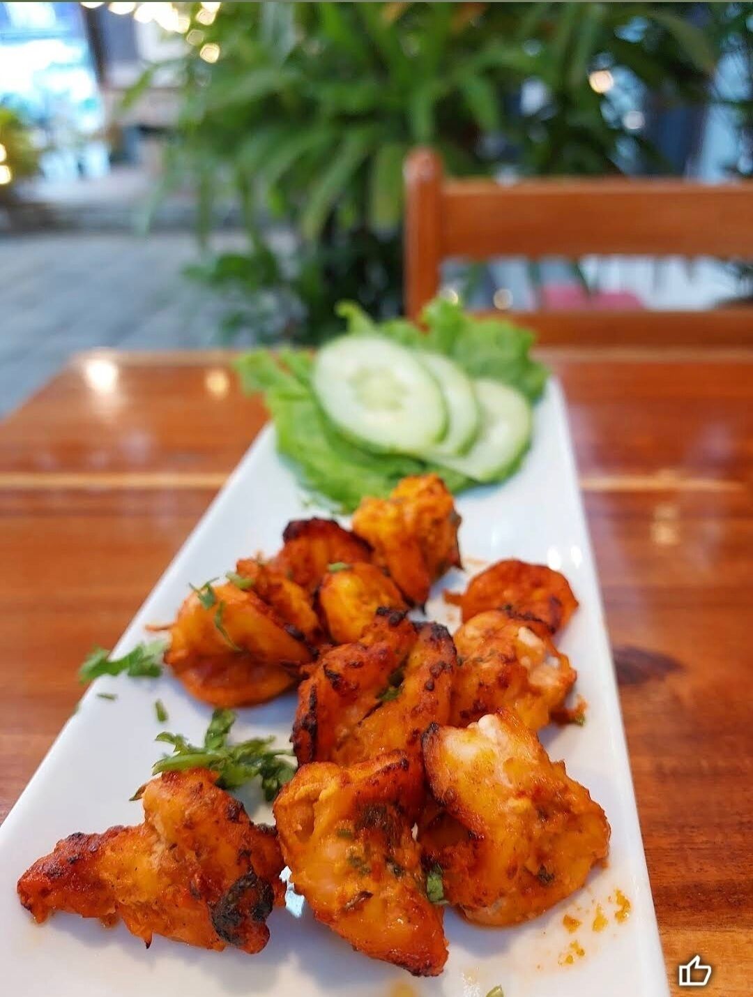 Un plato de alitas de pollo a la parrilla acompañado de rebanadas de pepino y lechuga.