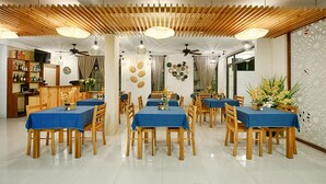 Un espace repas comprenant plusieurs tables et chaises, un plafond en bois et des panneaux décoratifs sur les murs.