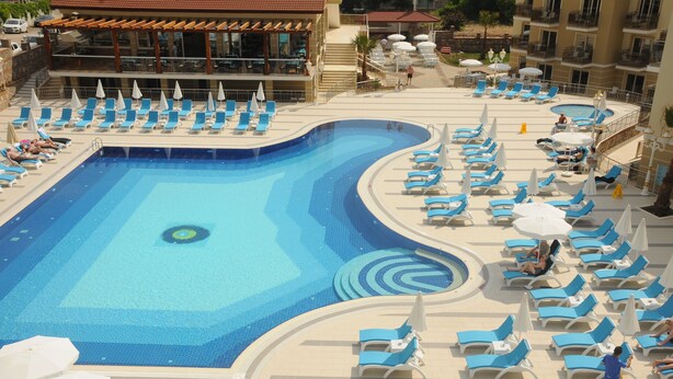 Une grande piscine entourée de chaises longues bleues et blanches et de parasols.