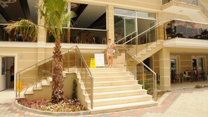 Un hôtel avec un palmier, un escalier et des places assises à l’extérieur.