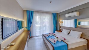 Une chambre d’hôtel avec un lit, un bureau, une télévision et une fenêtre avec des rideaux.