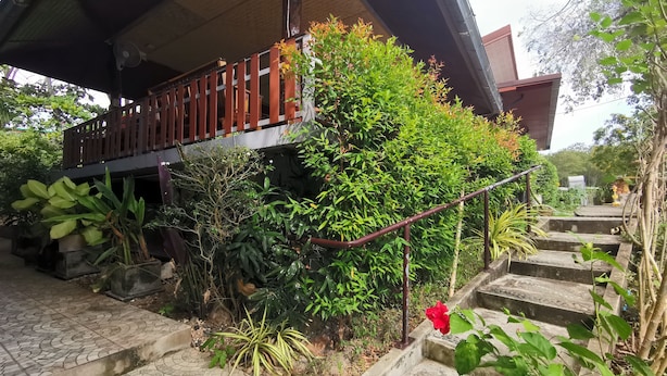 A covered outdoor area with a wooden deck, steps leading up to a building, and various plants. - Krabi Avahill (Krabi)