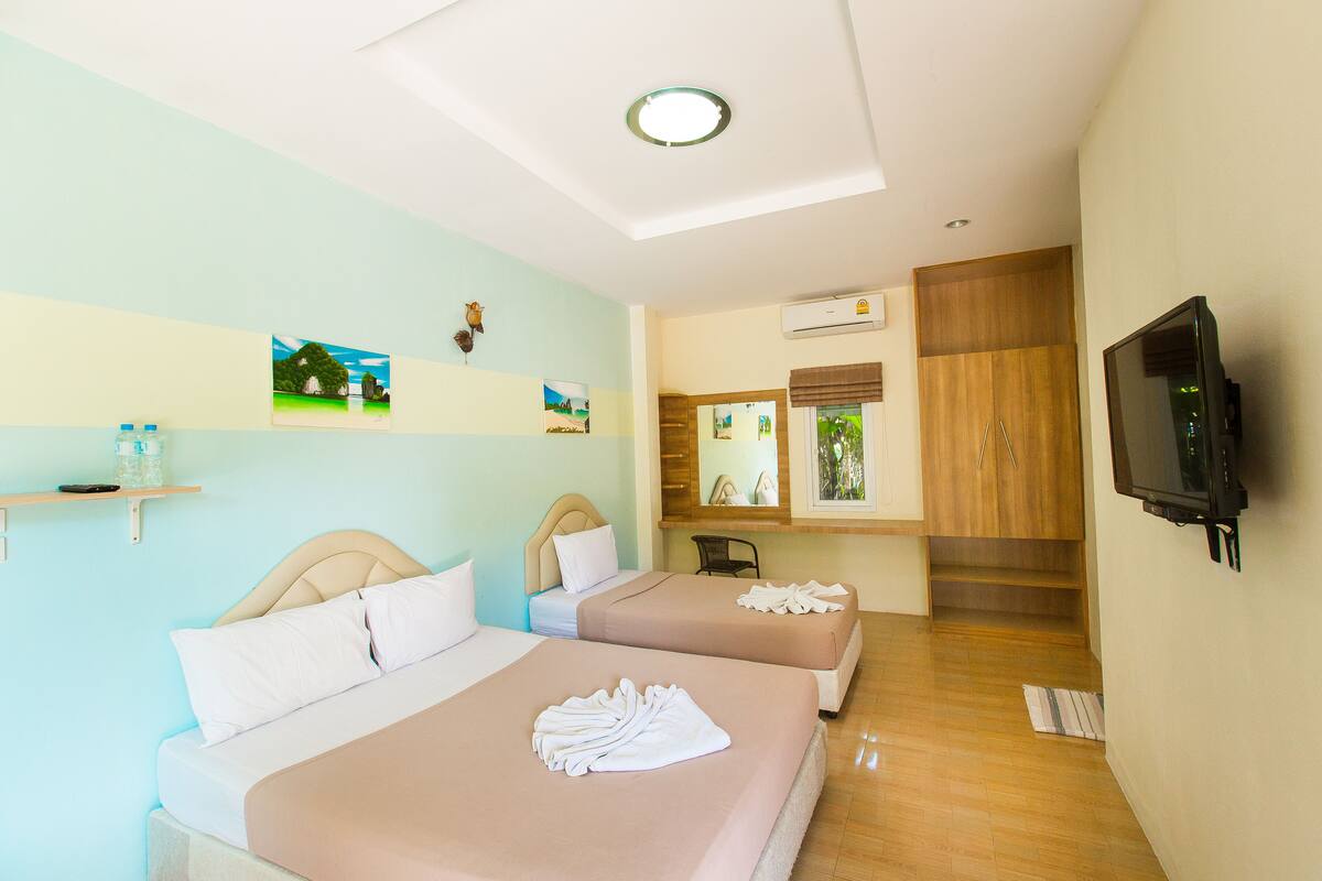 A hotel room with two beds, a TV, and artwork on the walls.