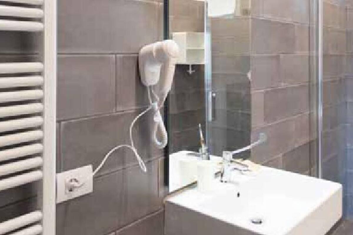 Een moderne badkamer met een witte wastafel, een douchecabine met glazen wanden en een handdoekhouder.
