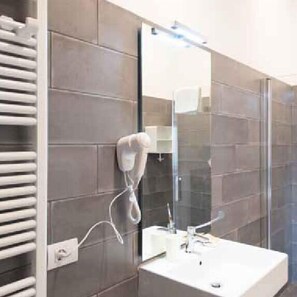 Une salle de bain moderne avec un lavabo blanc, une douche en verre et un porte-serviettes.