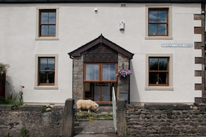 A two-story building with a stone facade, a central entrance with a wooden door, and a sign reading 'STANLEY LODGE FARM'. - Stanley Lodge Farmhouse (Lancaster)