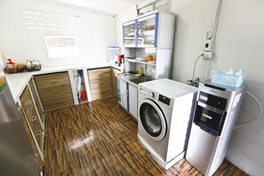 A compact kitchen with a washing machine, a refrigerator, and a sink.