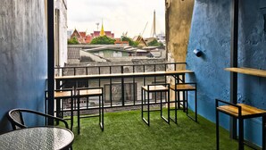 A balcony with a view of traditional buildings and a modern structure. - Zee Thai Hostel (Bangkok)