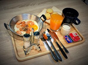 A breakfast tray with eggs, sausage, toast, orange juice, milk, and condiments.