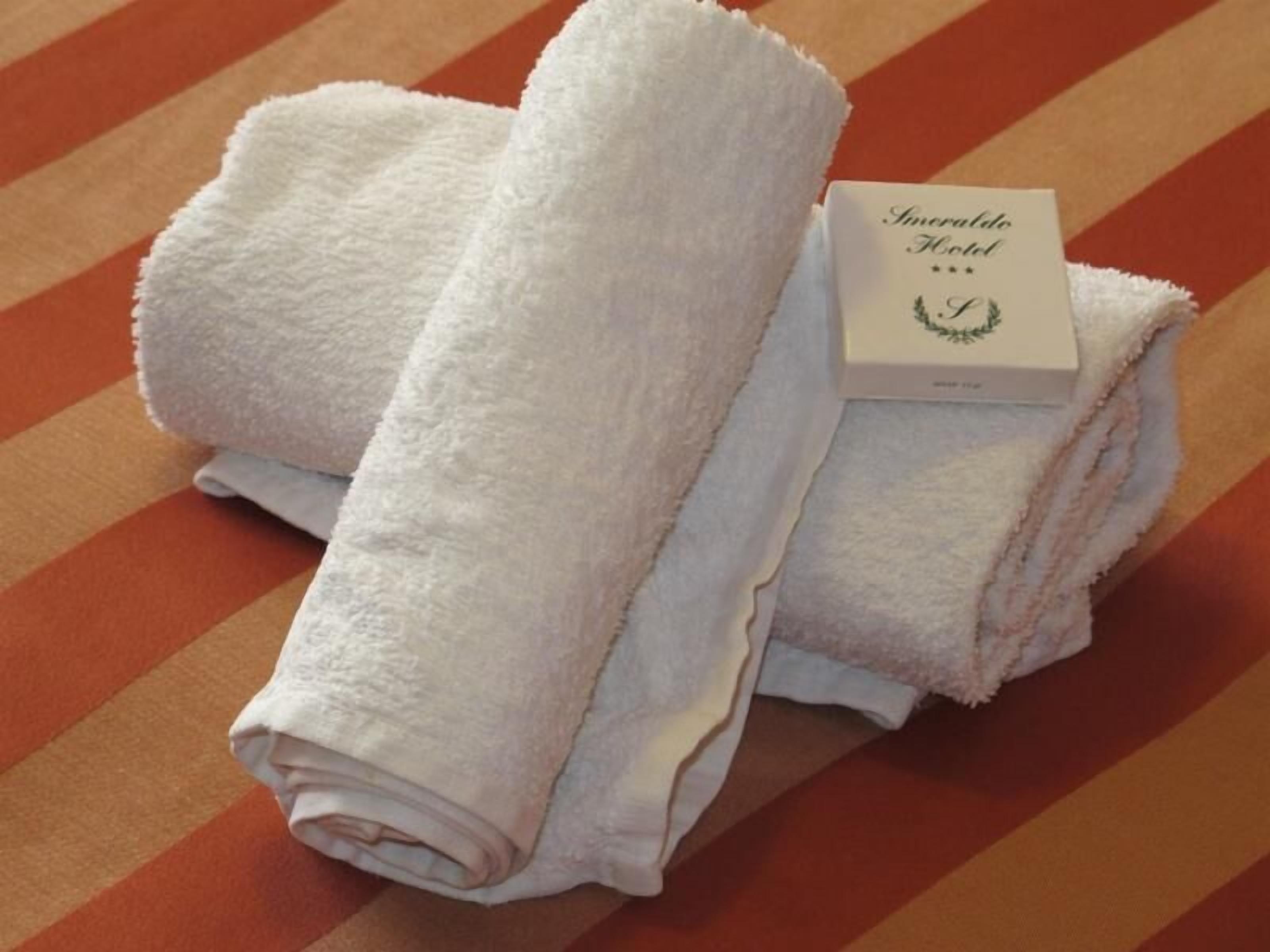 Une pile de serviettes blanches, avec une carte indiquant « Hôtel Amore ».