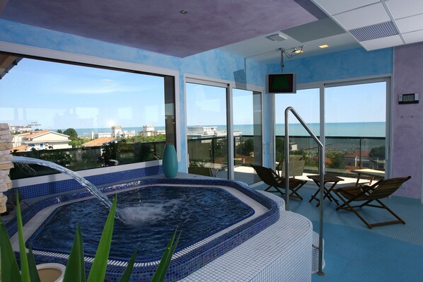 A hot tub area with a view of the sea, a TV, and lounge chairs. - Hotel Smeraldo (Jesolo)