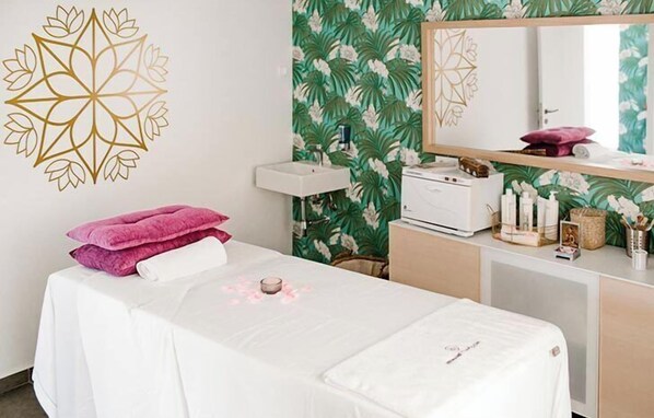 Una habitación con una cama, un tocador con espejo, un lavabo y una pared con estampado floral.