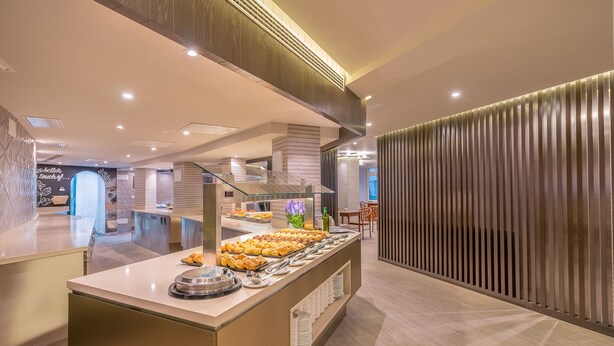 A buffet area with a variety of food items, a glass partition, and a modern interior design. - Hotel LIVVO Koala Garden (San Bartolomé de Tirajana)