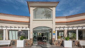 The entrance to Livvo Koala Garden Hotel with a glass door, stone pillars, and a tiled roof. - Hotel LIVVO Koala Garden (San Bartolomé de Tirajana)