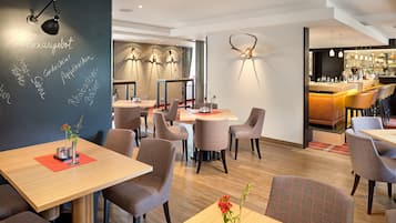 A modern restaurant with wooden tables and chairs, a bar area, and decorative wall art.