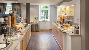 Una cocina moderna con una encimera amplia, diversos alimentos y una ventana con vistas a la vegetación.