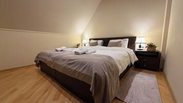 A neatly made bed with pillows and a bedside table with a lamp and a vase of flowers.