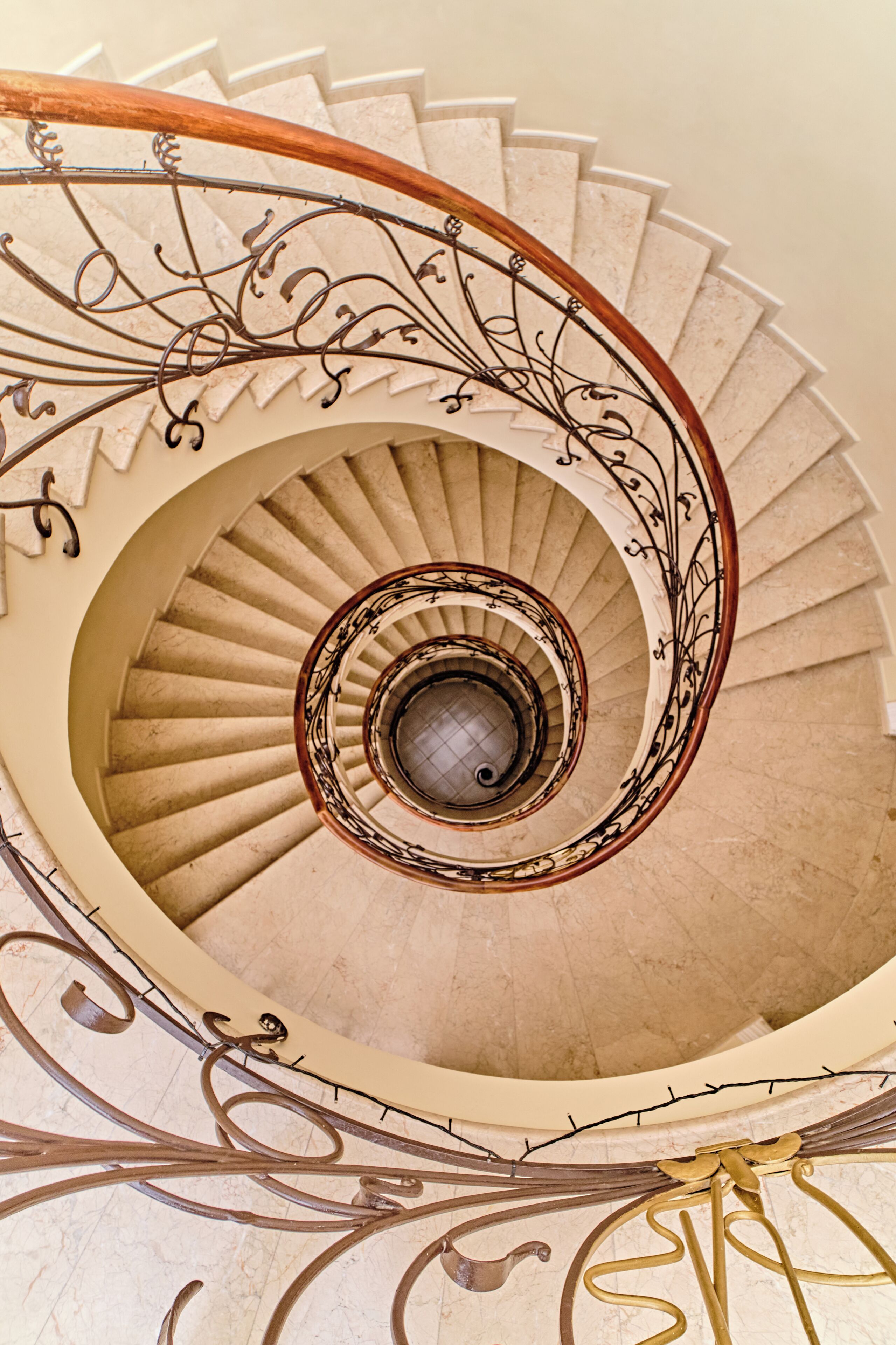 Eine Wendeltreppe mit aufwendiger Metallreling und einer Holzhandläufe.