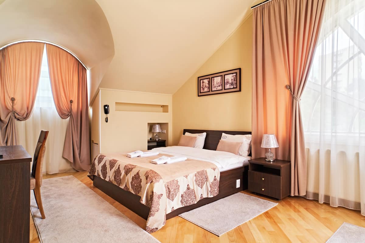 A bedroom with a bed, nightstands, a desk, and a chair.
