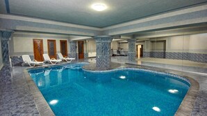 An indoor swimming pool with marble flooring and walls, surrounded by lounge chairs. - S&L Boutique Hotel  (Tbilisi)