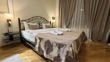 Una cama bien hecha con una colcha estampada, una mesita de noche con lámpara y una ventana con cortinas.