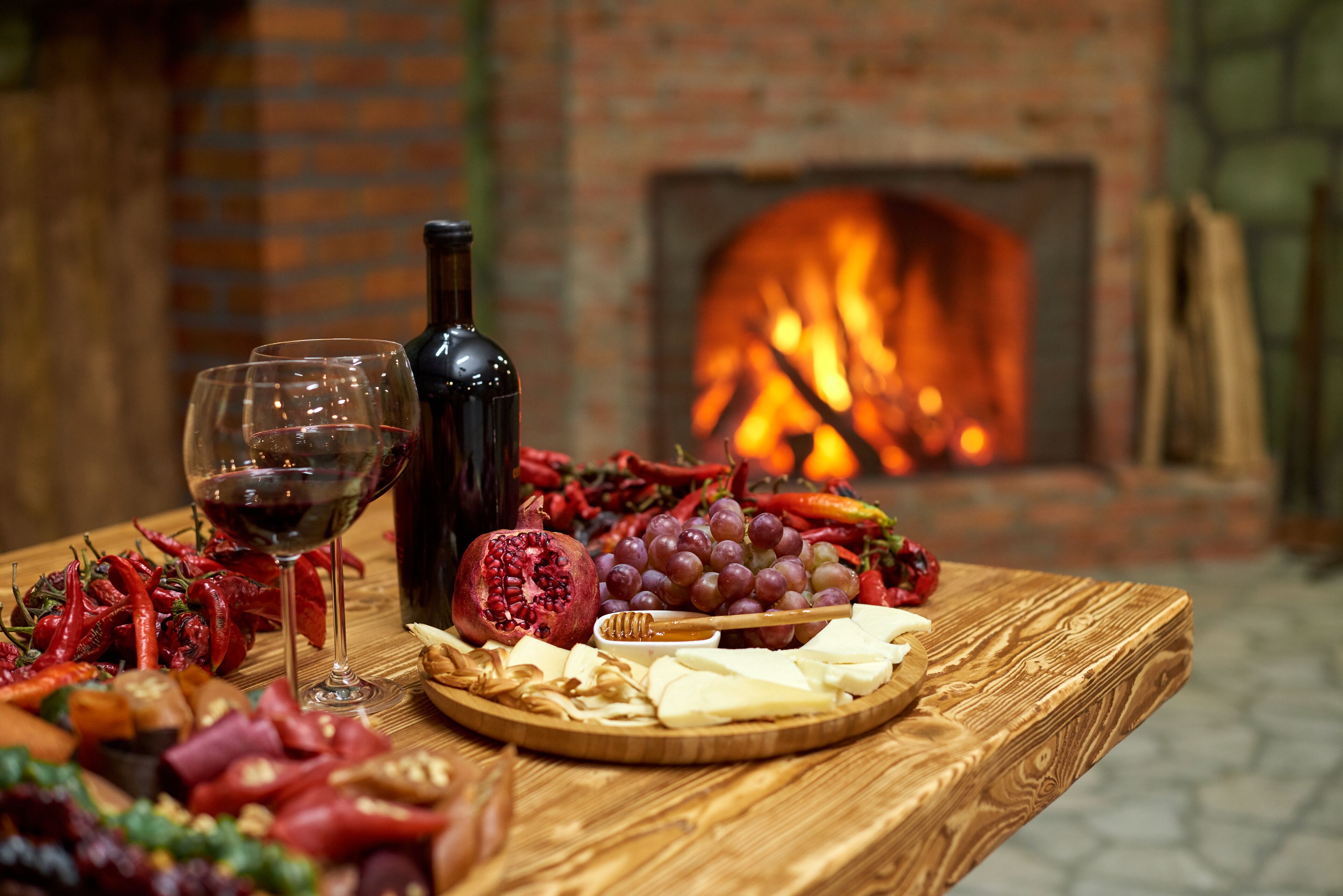 A wooden table with a charcuterie board, wine bottle, and glasses.