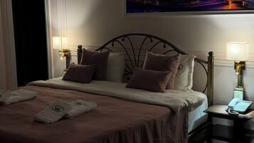 Habitación de hotel con una cama, dos mesitas de noche, una lámpara y vistas de la ciudad en la pared.