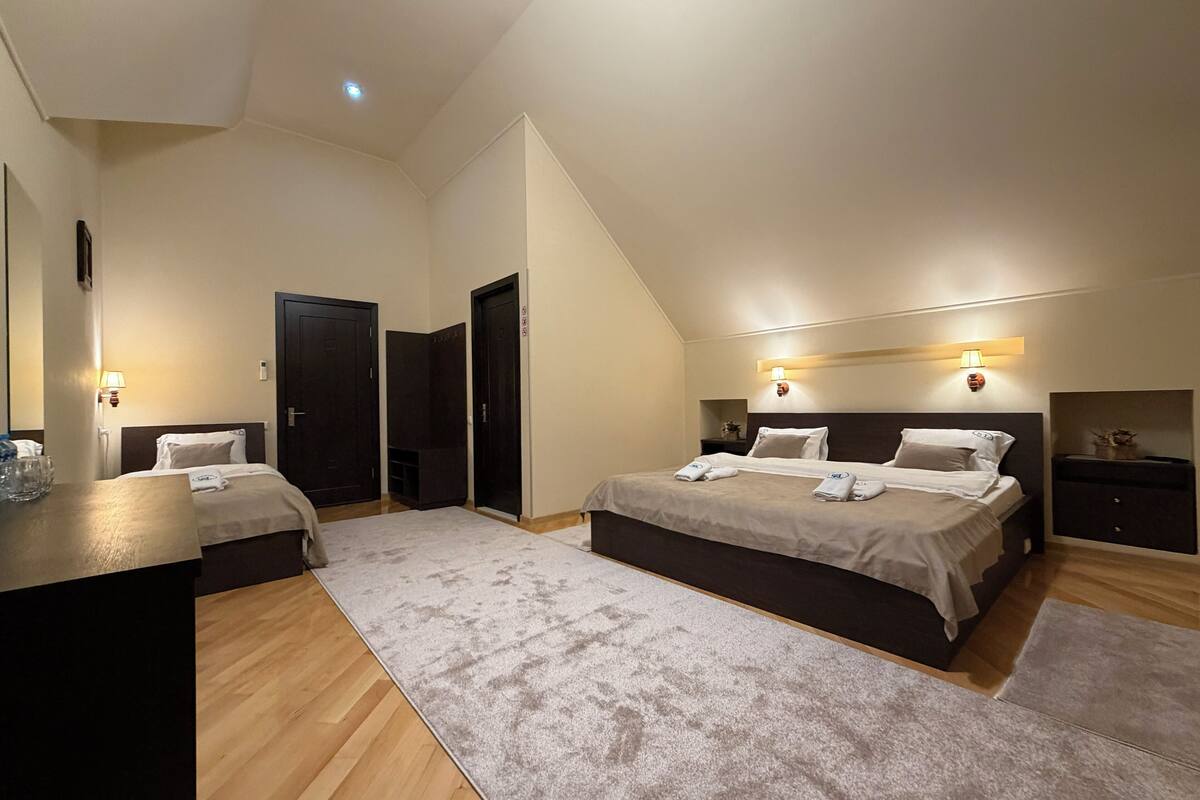 A modern hotel room with two beds, a desk, and a large mirror.