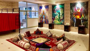Um quarto com tapete vermelho, almofadas estampadas e uma mesa central.