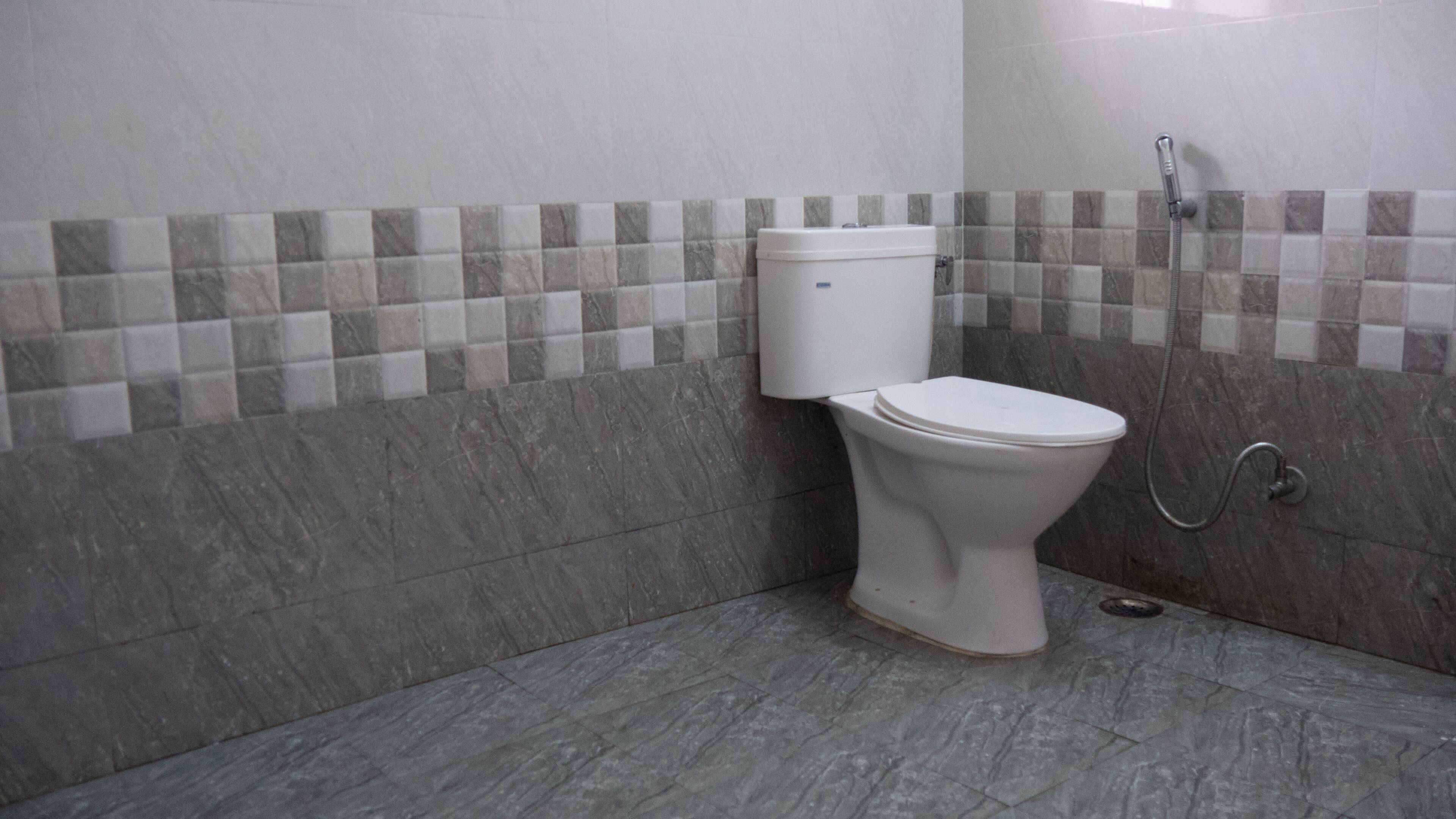 A bathroom with a toilet, a shower, and tiled walls.