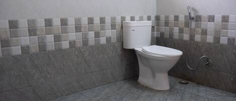 Un baño con inodoro, ducha y paredes con azulejos.