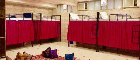 A room with two bunk beds, each with a red bedspread, and a patterned carpet.