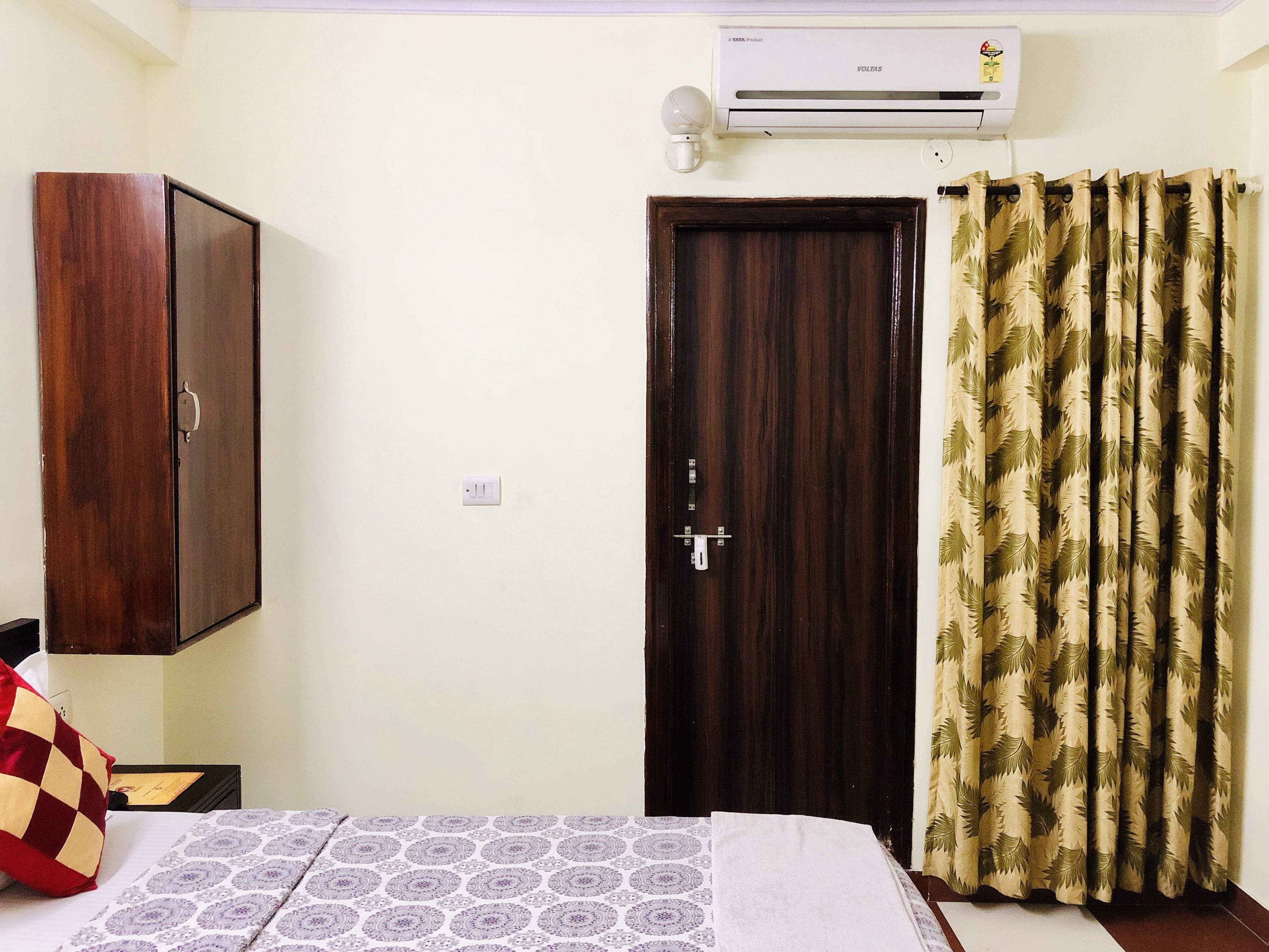Quarto com cama, guarda-roupa, porta e cortina.