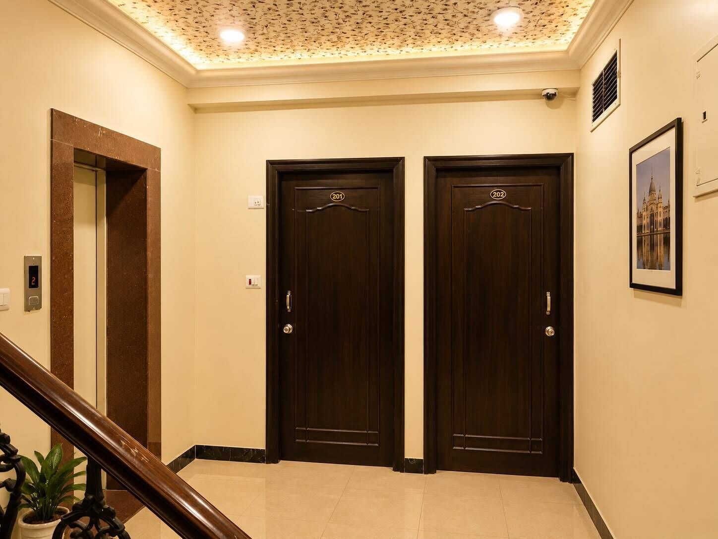 Un pasillo con dos puertas de madera oscura, una escalera con barandilla y un techo con diseño decorativo.