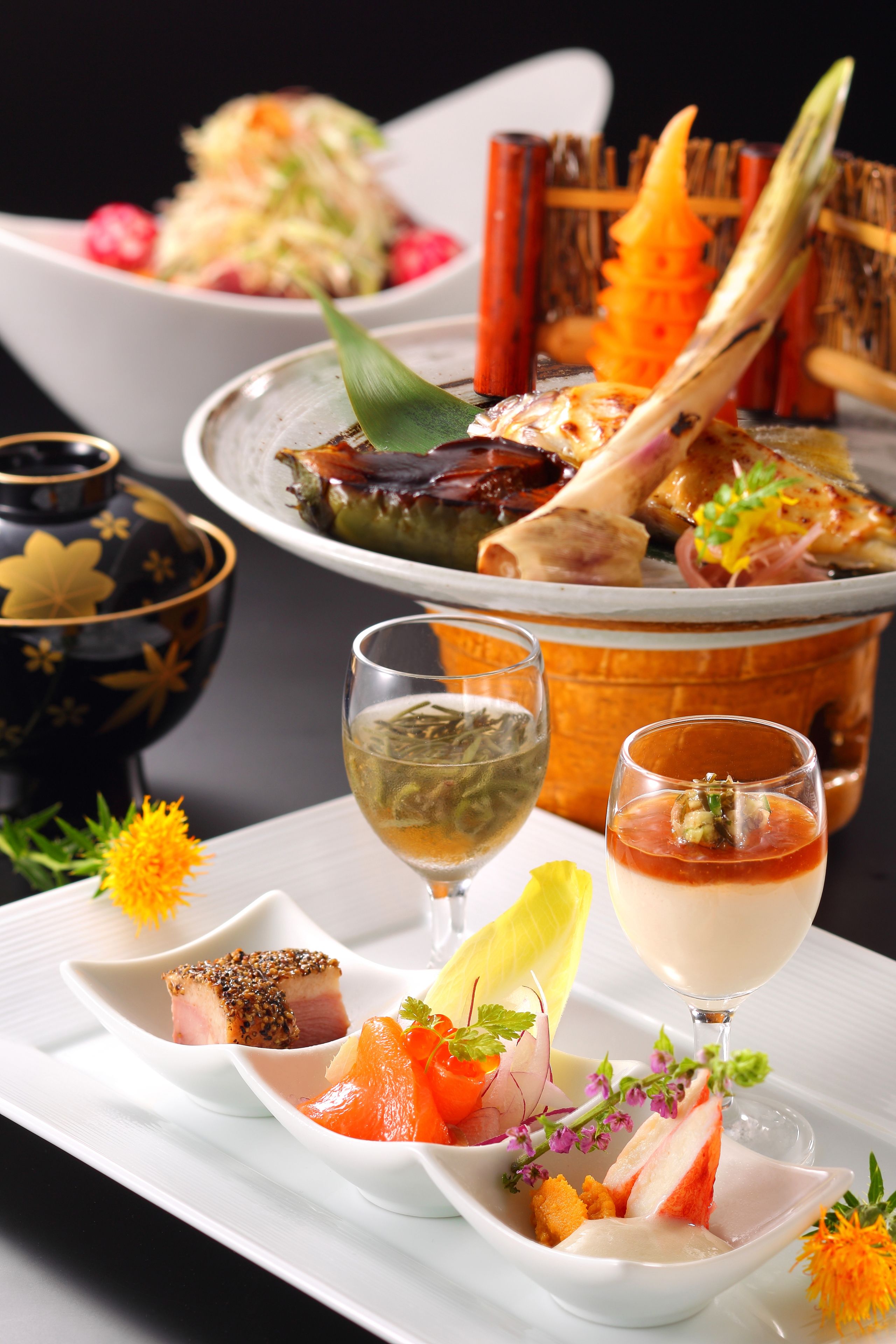 A variety of dishes including sashimi, a bowl of soup, and a teapot.