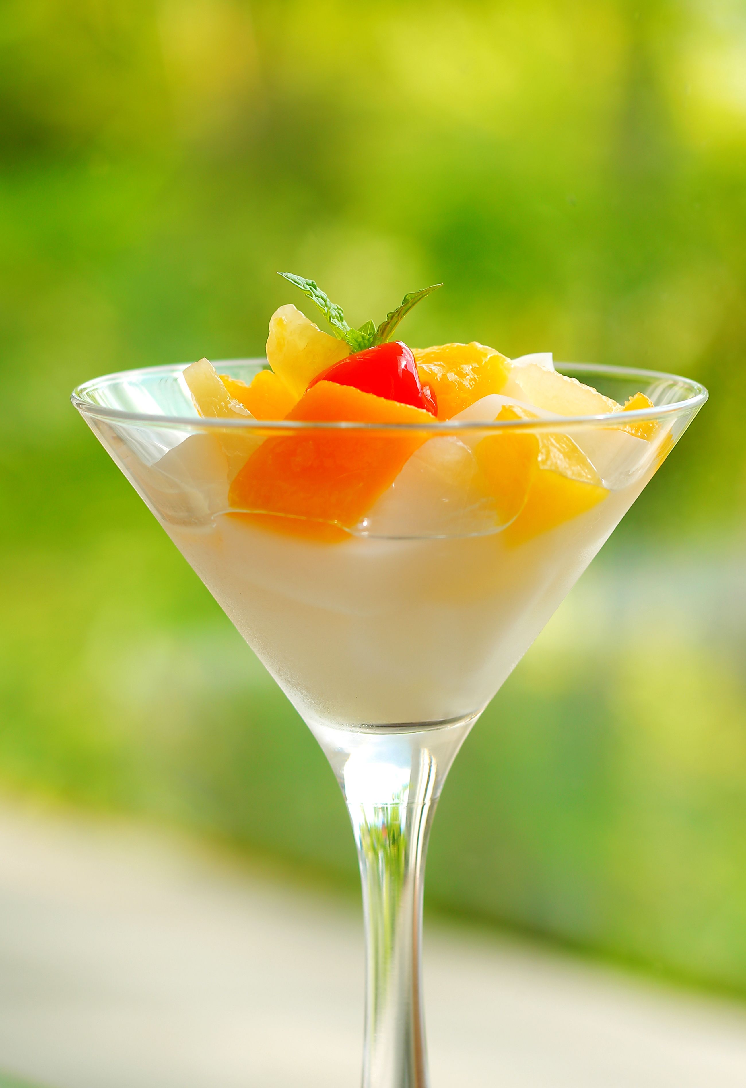 A dessert in a martini glass with fruit on top.