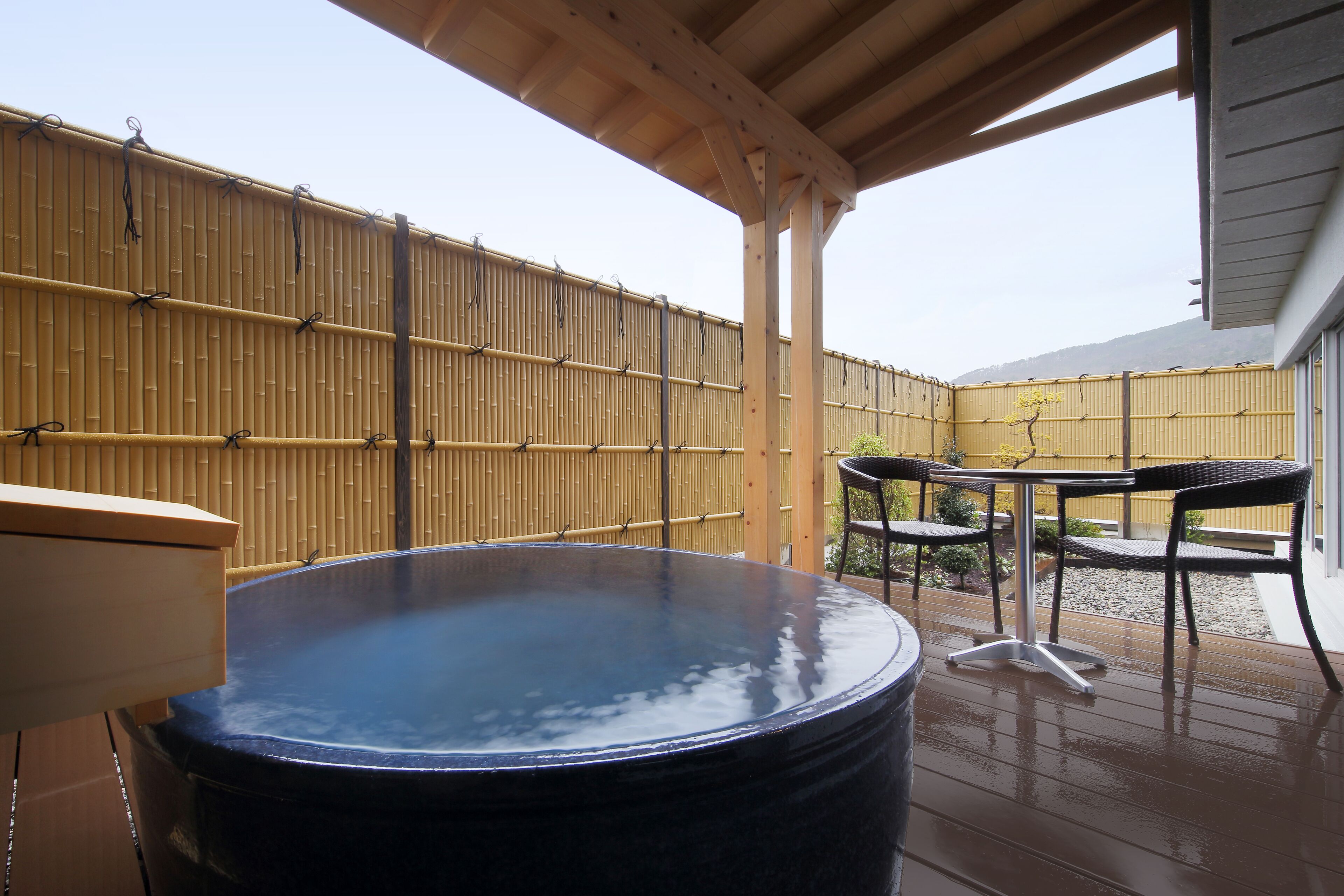 A hot tub on a wooden deck with a bamboo fence in the background.