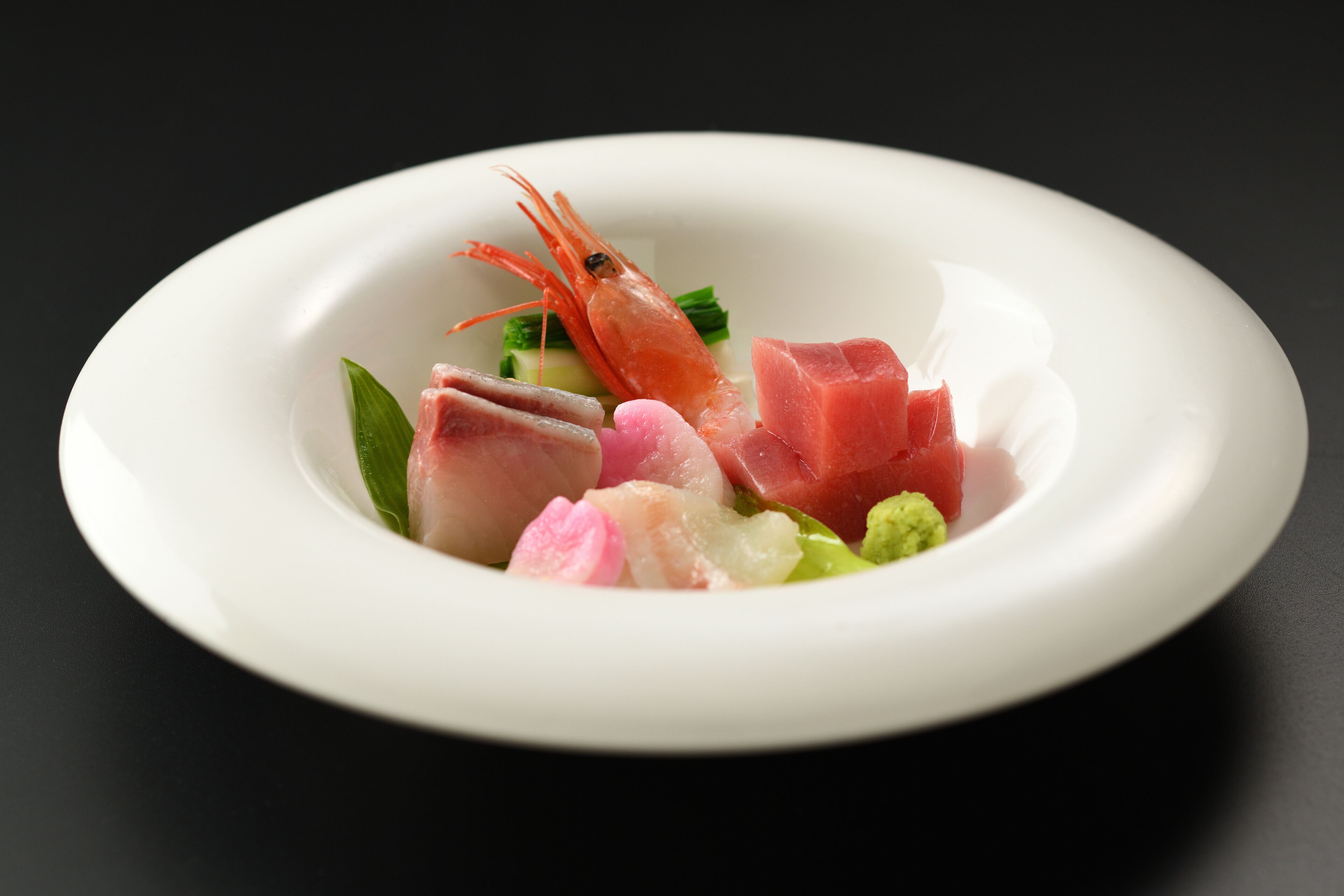 A white plate with various seafood items including shrimp, fish, and possibly some vegetables.