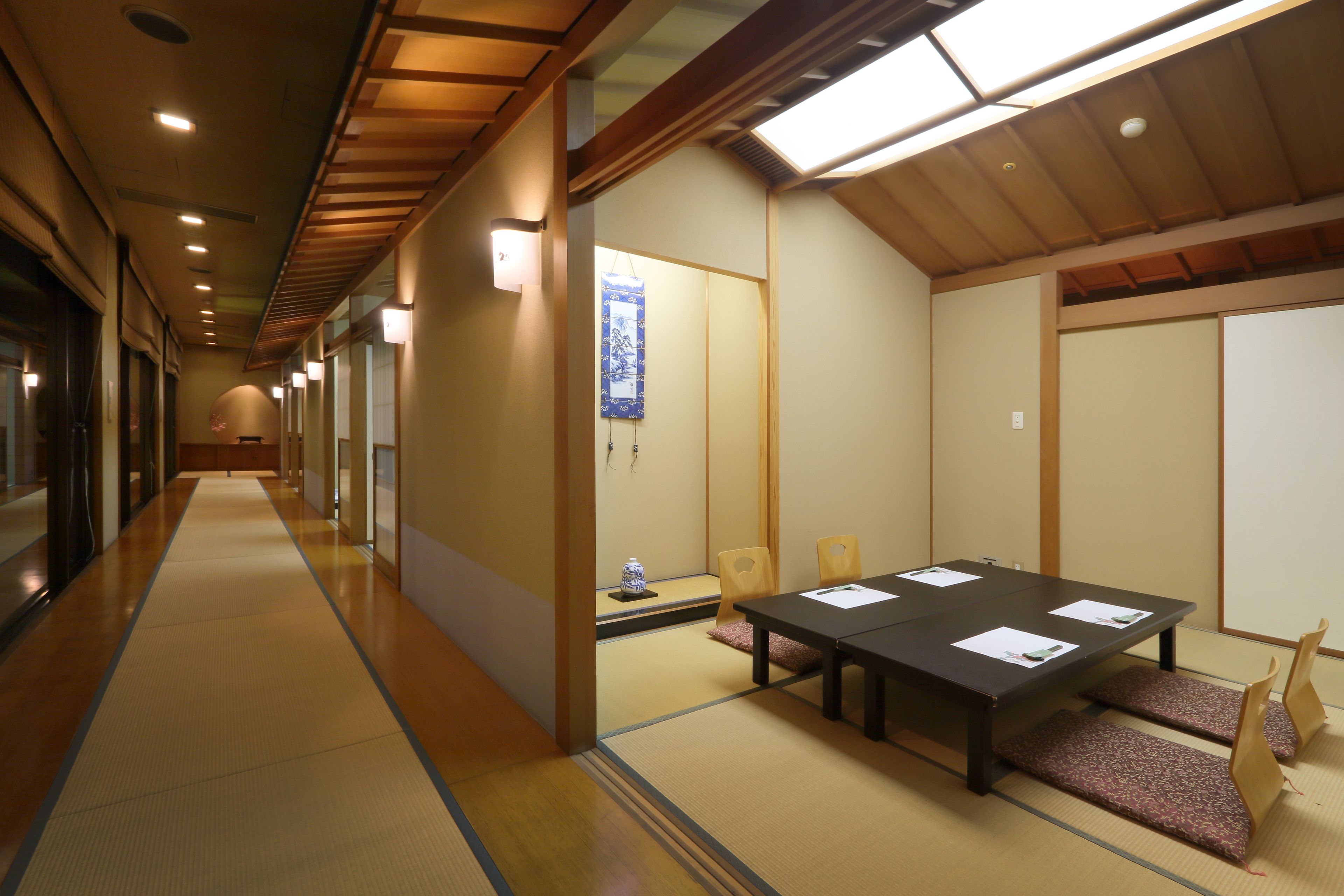 A traditional Japanese room with tatami flooring, a low table with papers, and sliding doors.