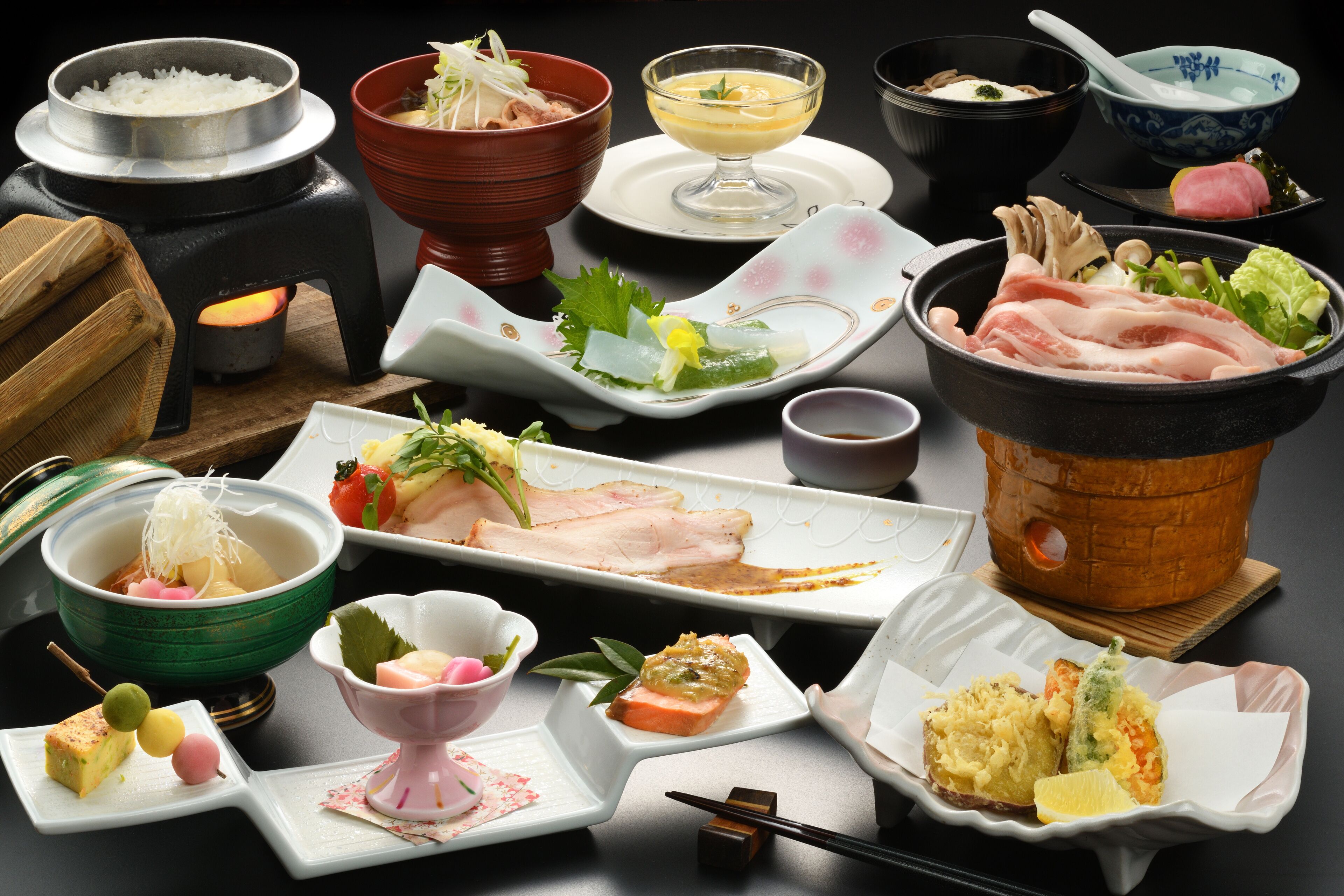 A variety of Japanese dishes including sushi, sashimi, and tempura, arranged on a table.