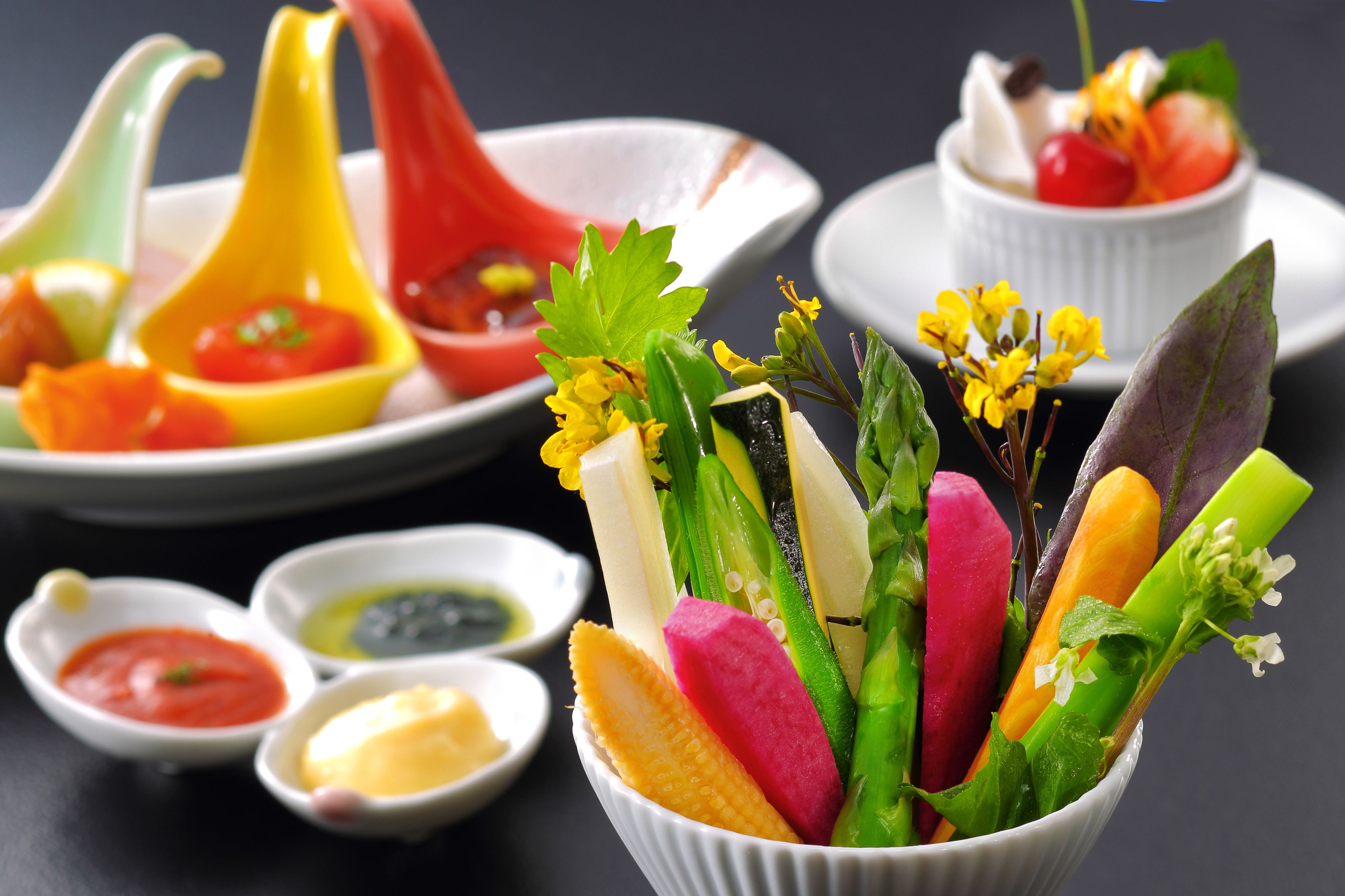 Un grand saladier rempli de légumes colorés et de petits bols de sauces.
