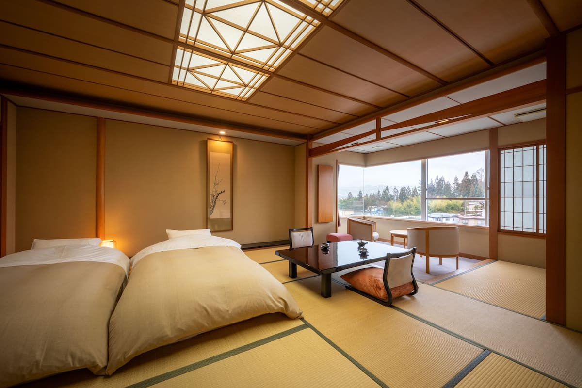 Ein traditioneller japanischer Raum mit Tatami-Boden, einem niedrigen Tisch und einer Couch.