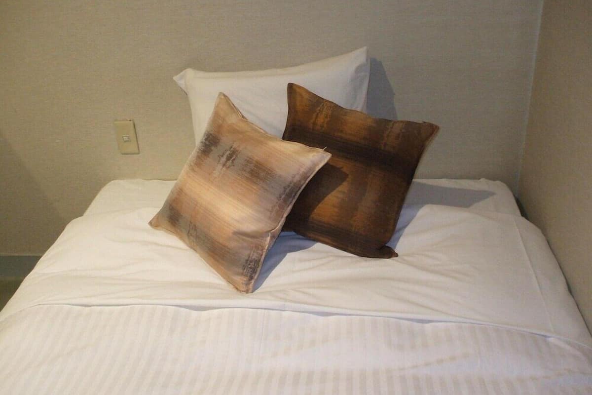 Ein Bett mit weißer Bettwäsche und zwei Kissen.