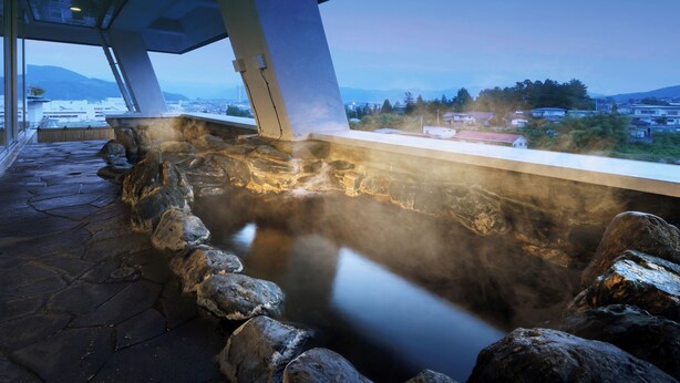 A stone hot spring area with a view of a cityscape and mountains in the background. - Kaminoyama Azumaya (Kaminoyama)