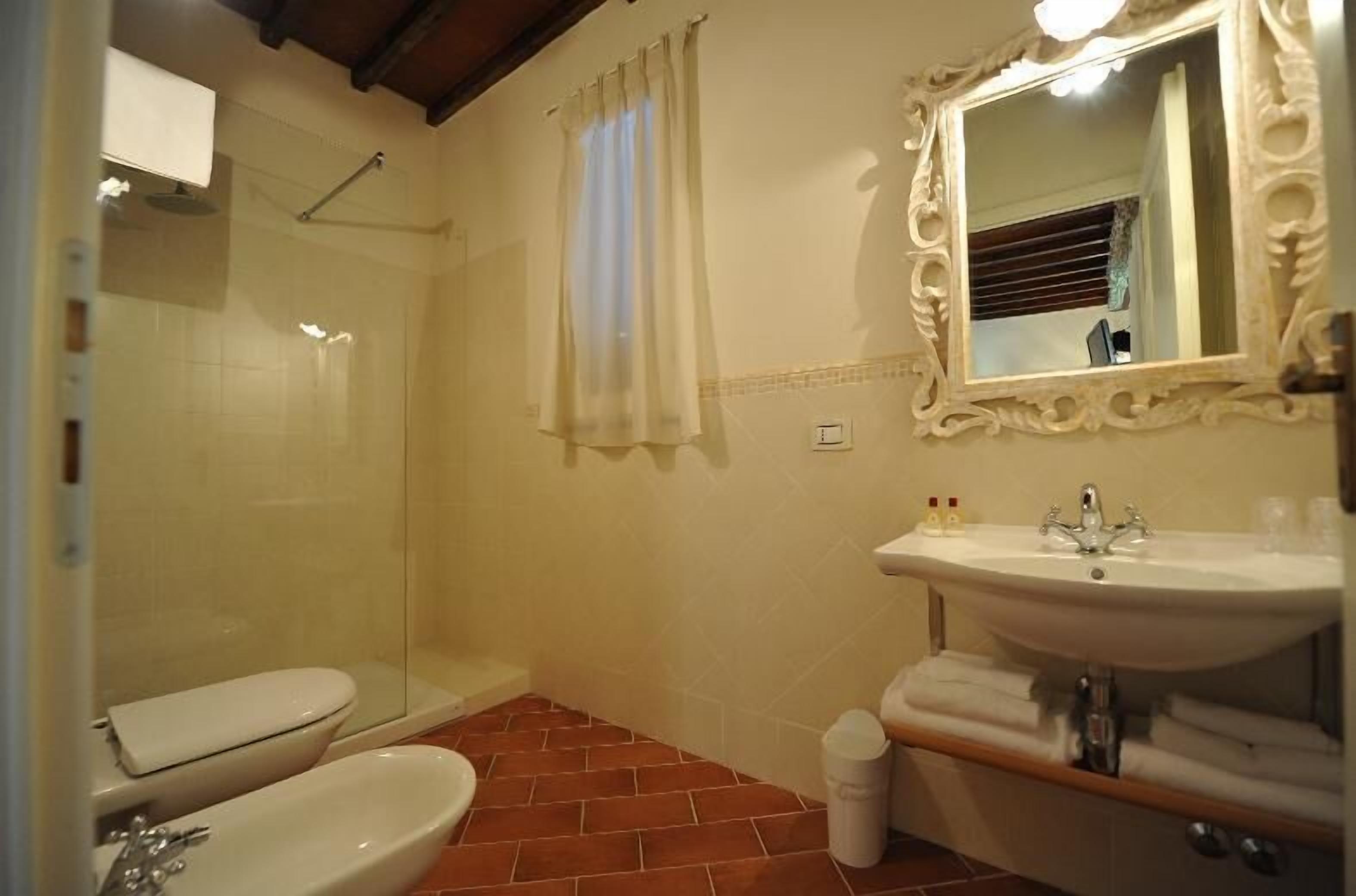 A bathroom with a toilet, bidet, sink, and mirror.