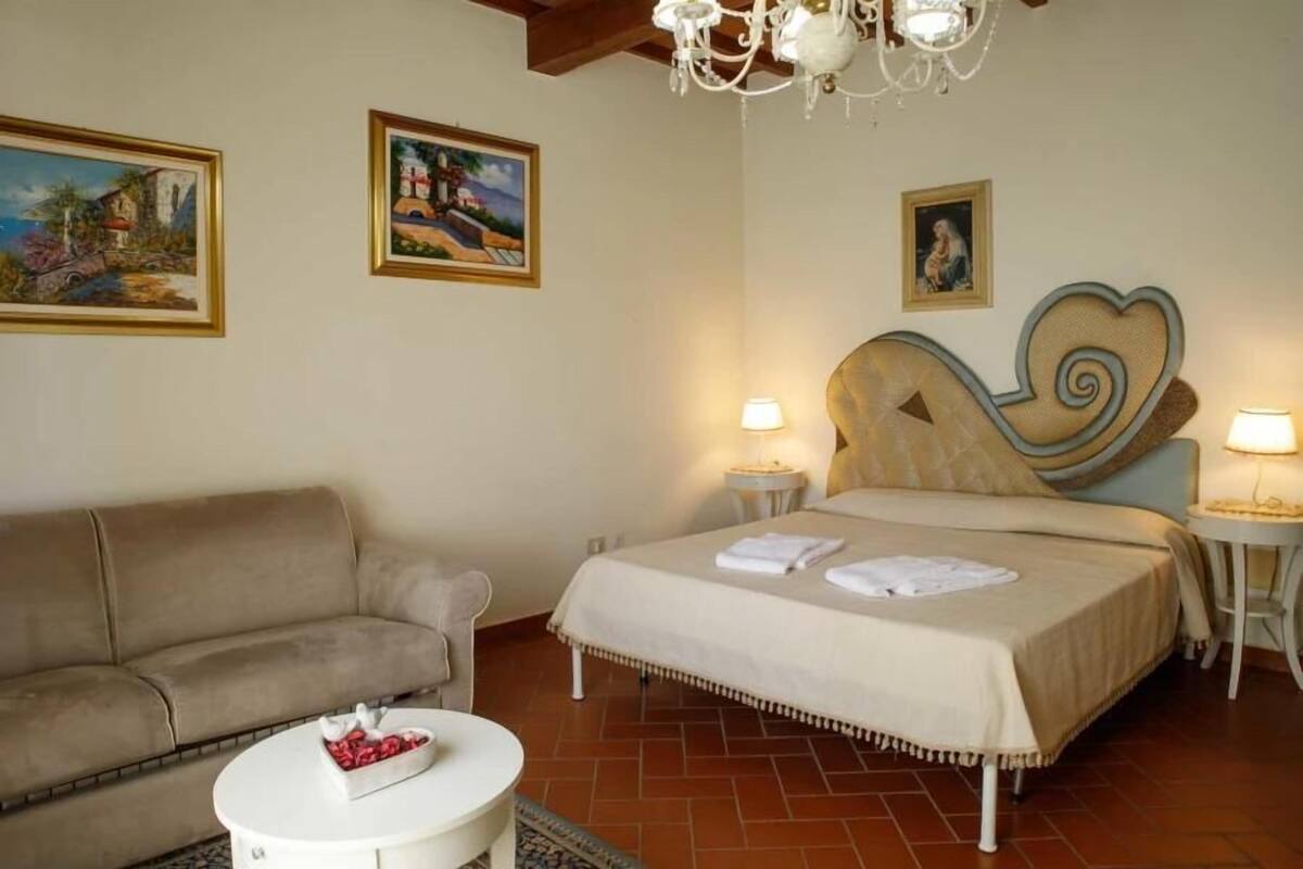 A bedroom with a bed, a sofa, a round table, and two bedside lamps.